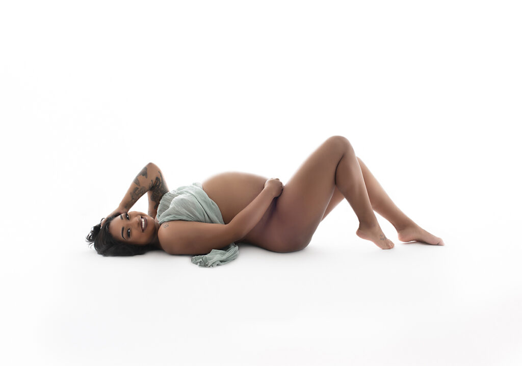 Columbus GA maternity session with pregant woman lying down on white background with a scarf covering her.