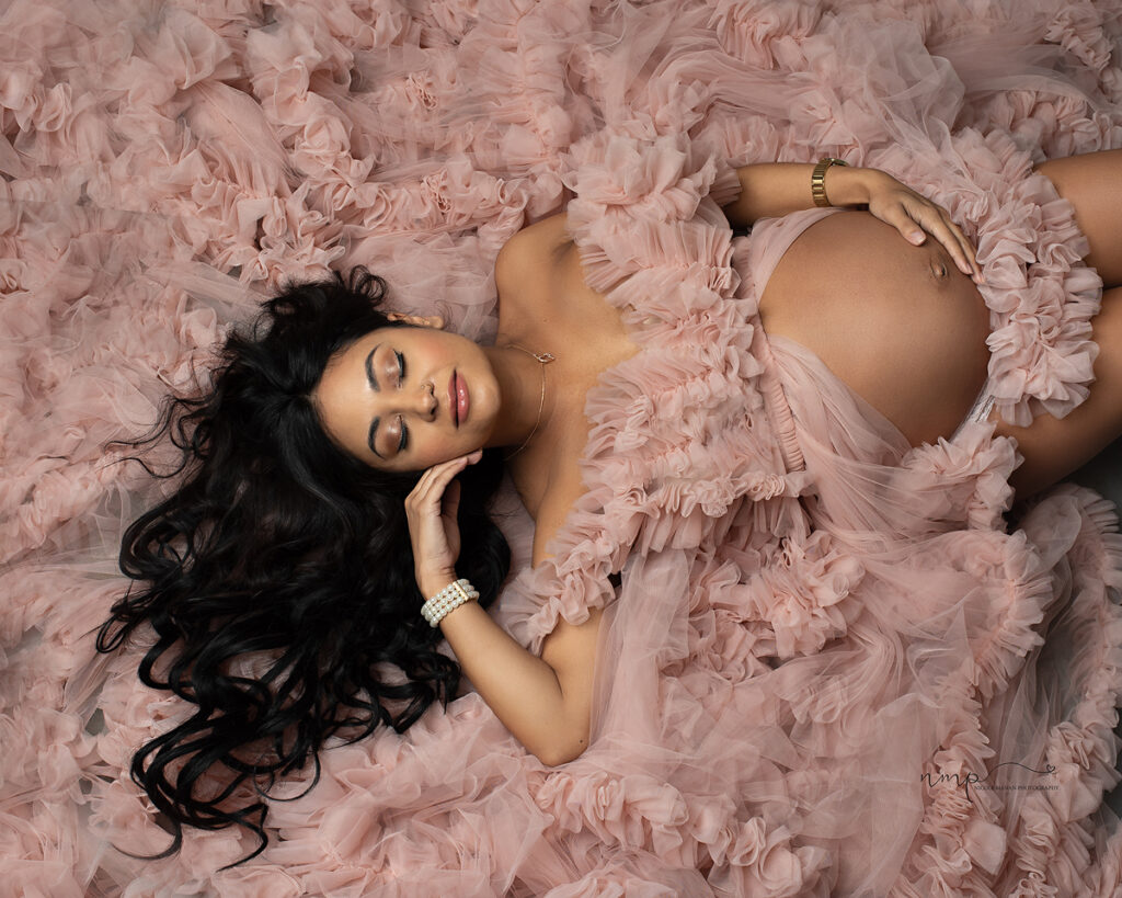 Pregnant woman in beautiful ruffle maternity dress lying on the floor during her Columbus GA maternity session