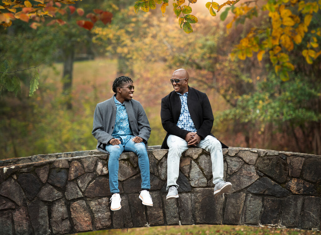 A father and his son sitting on a bridge and laughing during their photo session in Columbus GA