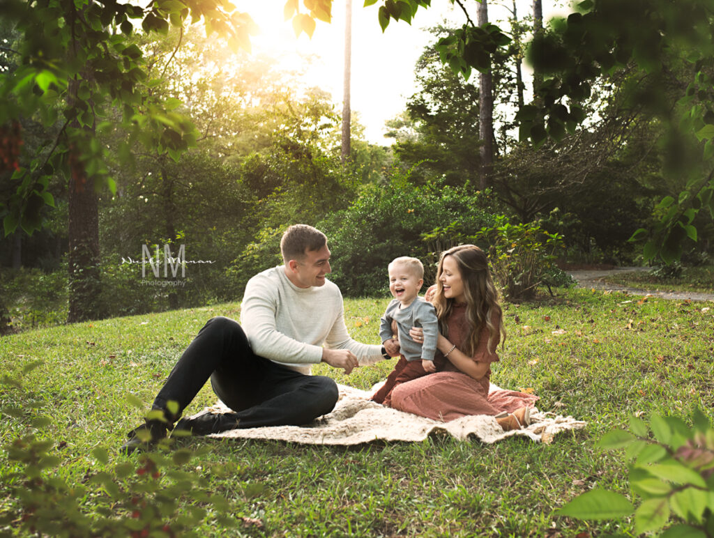 Family sitting in a park interacting with the toddler son during their fall family session